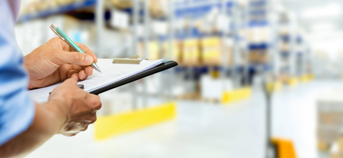 logistics service man writing documents on clipboard in warehouse