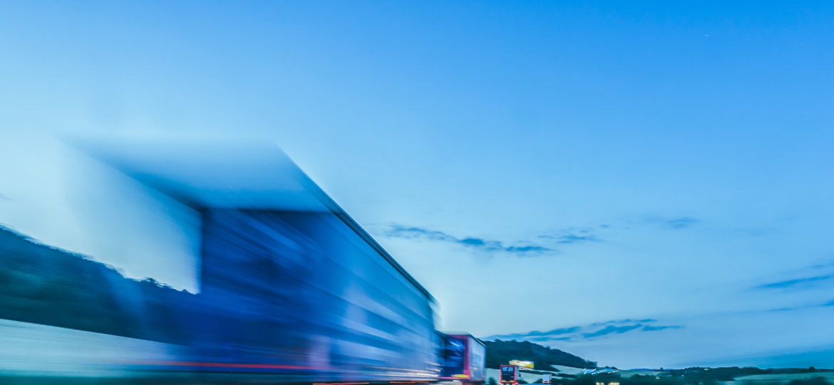 Background photograph of a highway. Truck on a motorway, motion blur, light trails. Evening or night shot of trucks doing logistics and transportation on a highway.